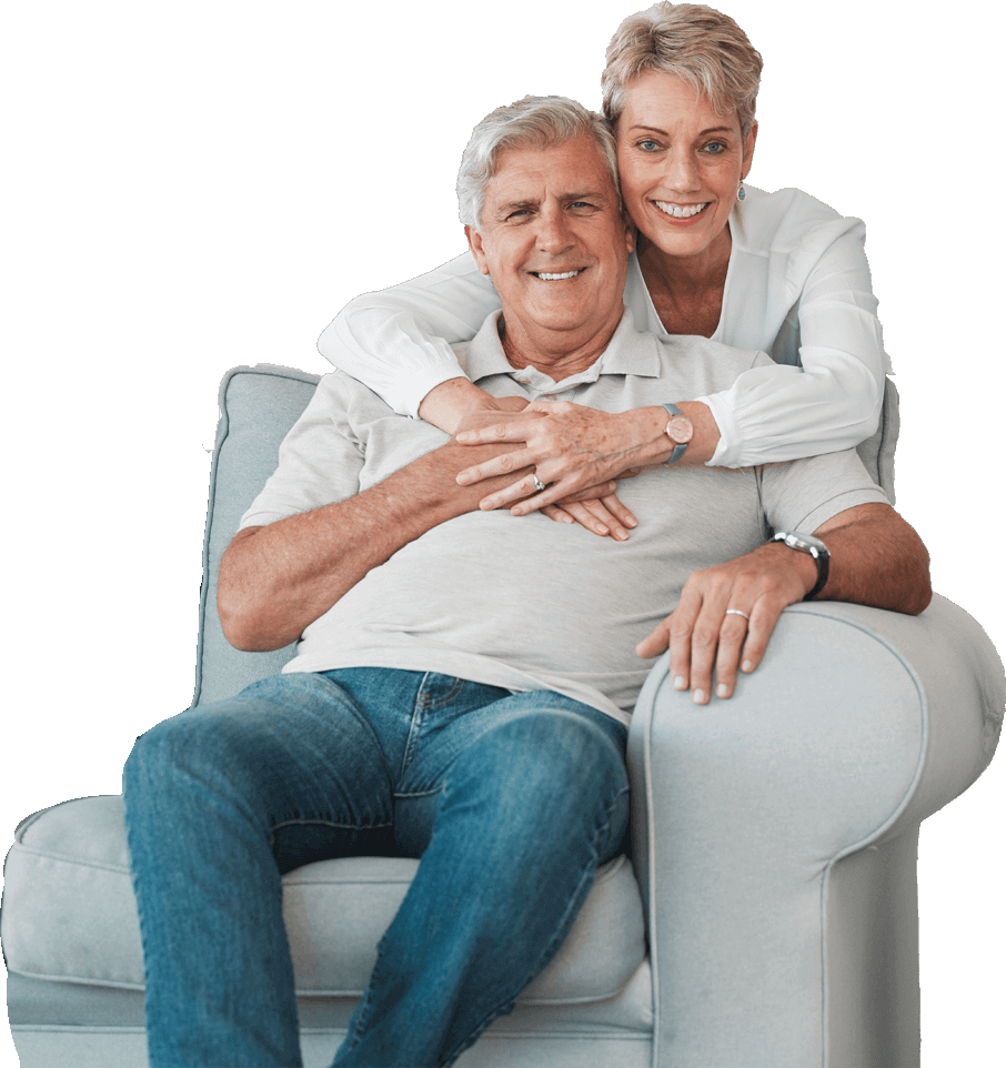 An elderly couple hugging and smiling on a sofa
